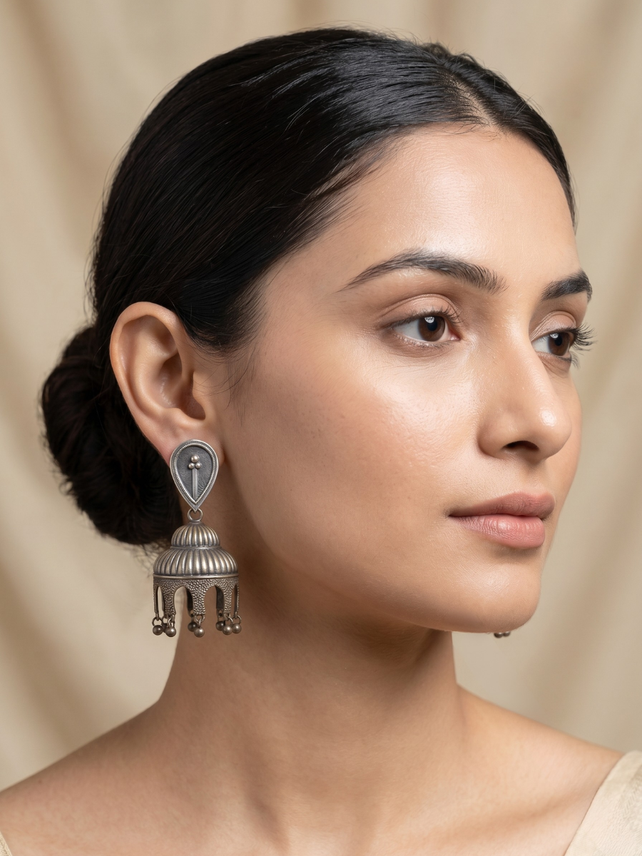 A model is wearing our Antique Bell Shaped German Silver Oxidised Jhumka Earrings