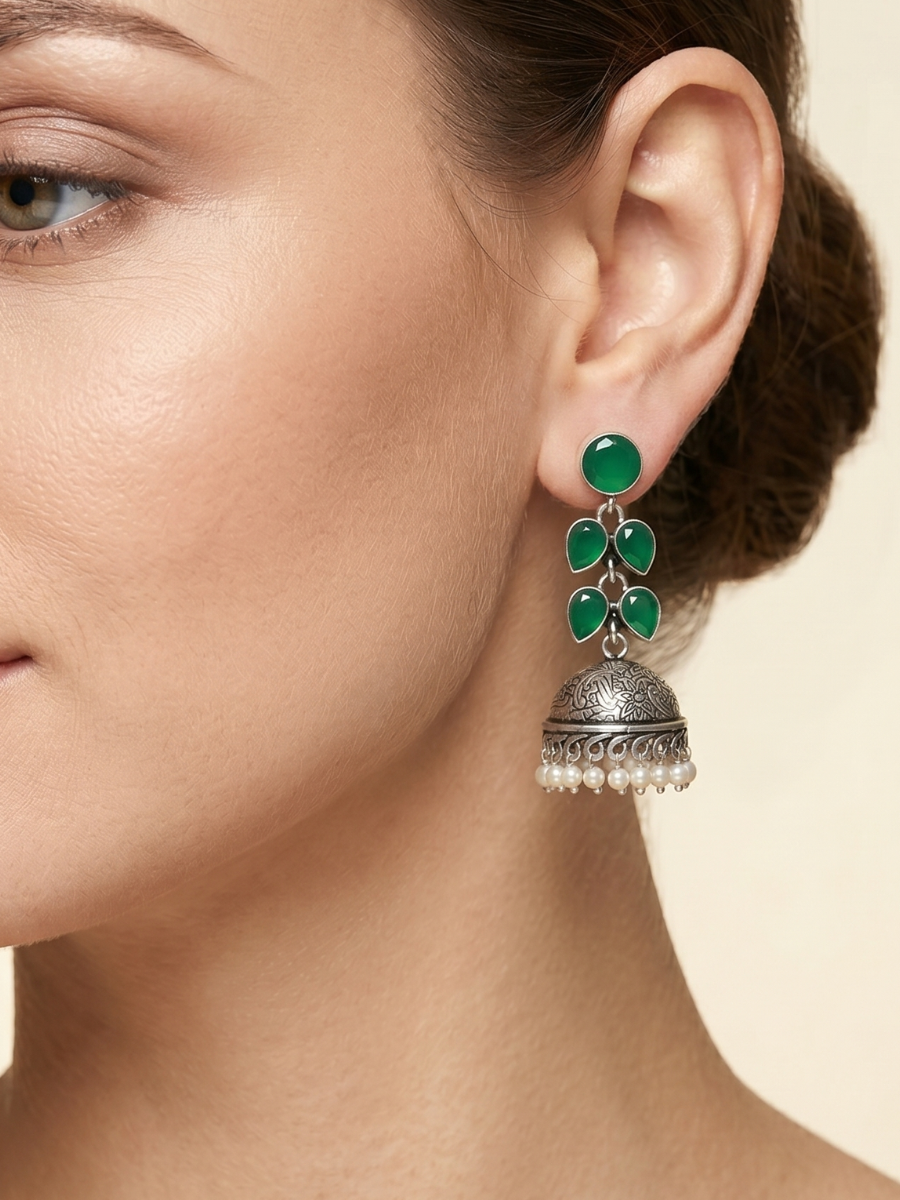 A model is wearing our Elegant Green Stones Oxidised Silver Drop Jhumka Earrings