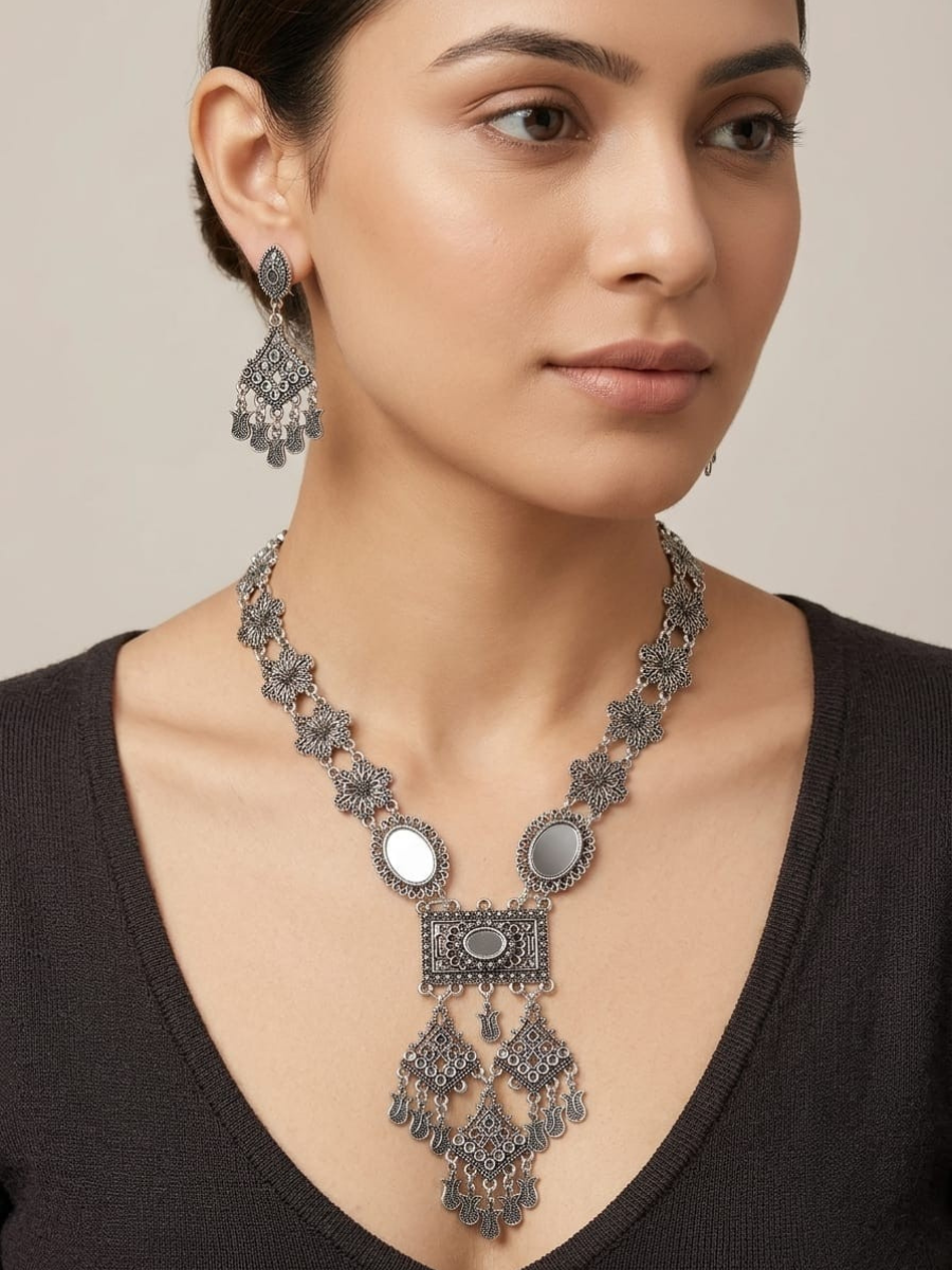 A model is wearing our Floral Pattern Long Oxidised Silver Mirror Necklace Set