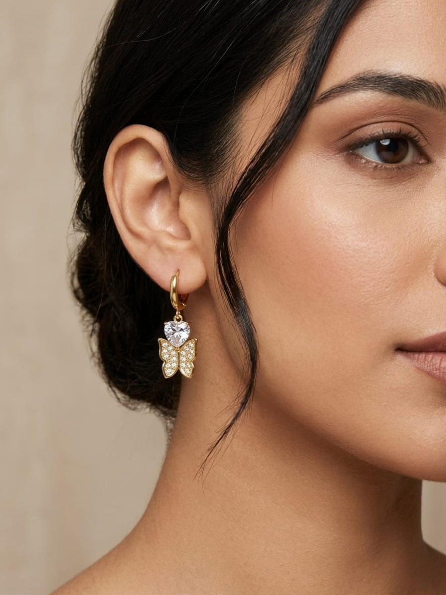 A model is wearing our Heart Stone Butterfly Drop Golden Huggie Hoop Earrings