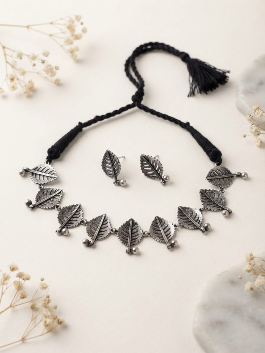 A silver-toned leaf pendant necklace with matching leaf earrings