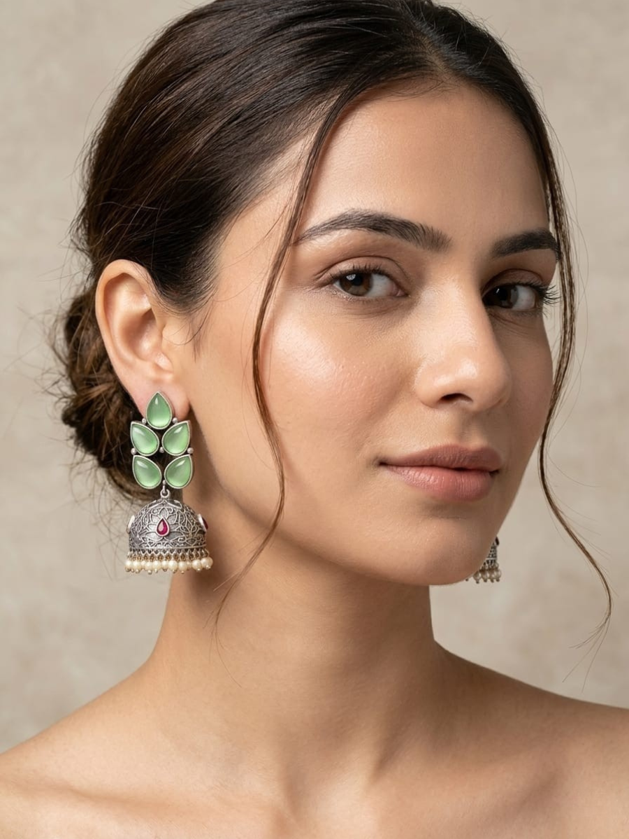 A model is wearing our Leaf Shaped Parrot Green Stones Big Oxidised Silver Jhumka Earrings