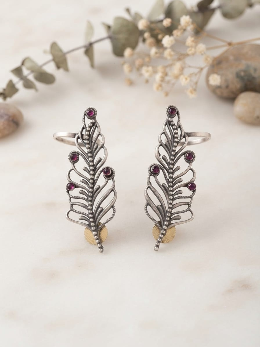 A pair of oxidised silver leaf-shaped earrings with small dark red gemstone accents