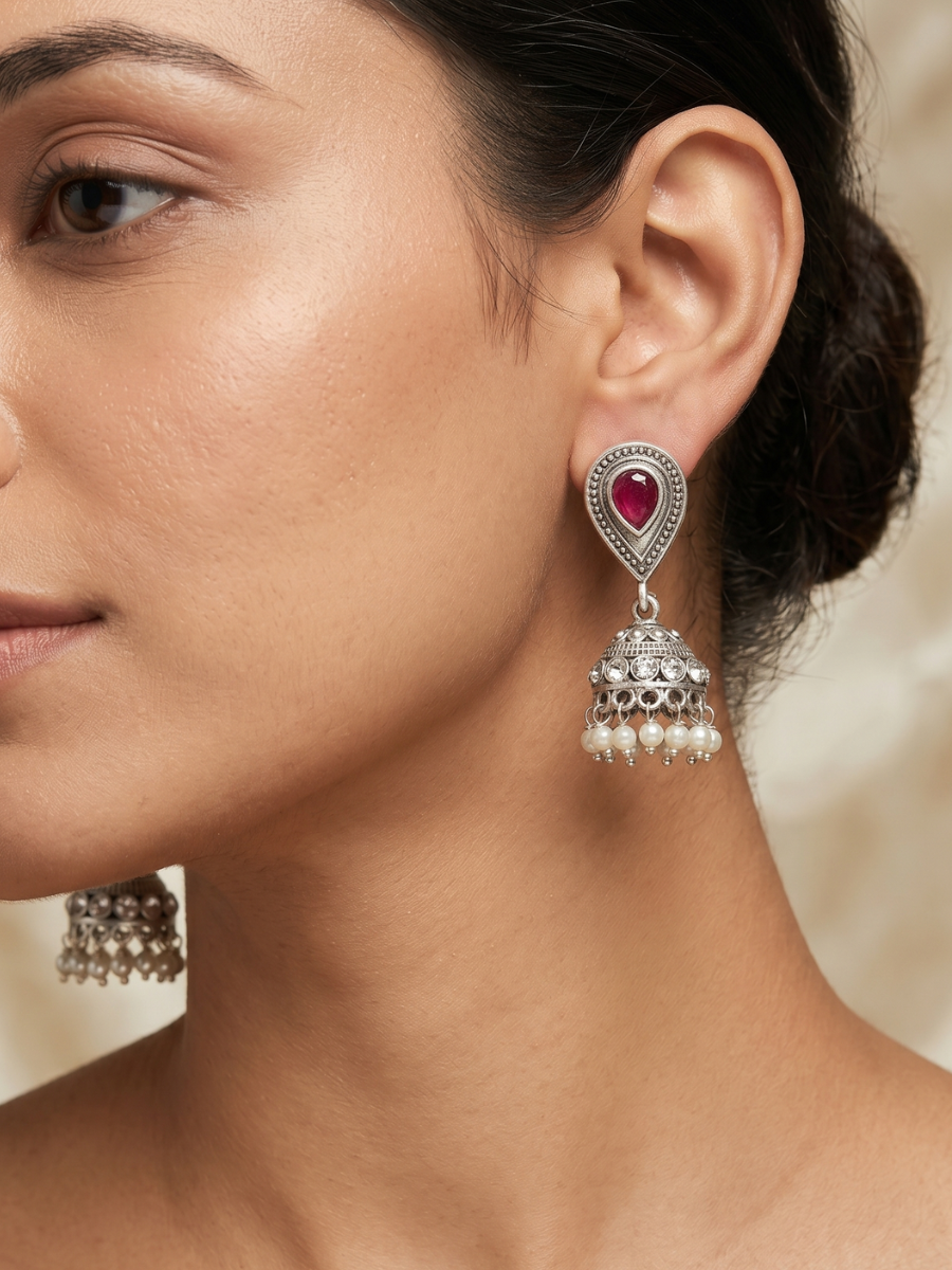 A model is wearing our Ruby Red Stone Studded Oxidised Silver Small Jhumka Earrings