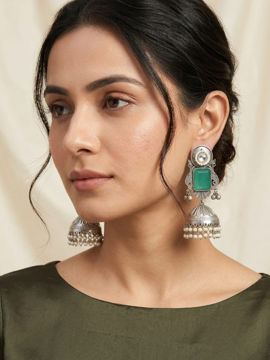 A model is wearing our Sea Green Stone Studded Oxidised Silver Long Jhumka Earrings