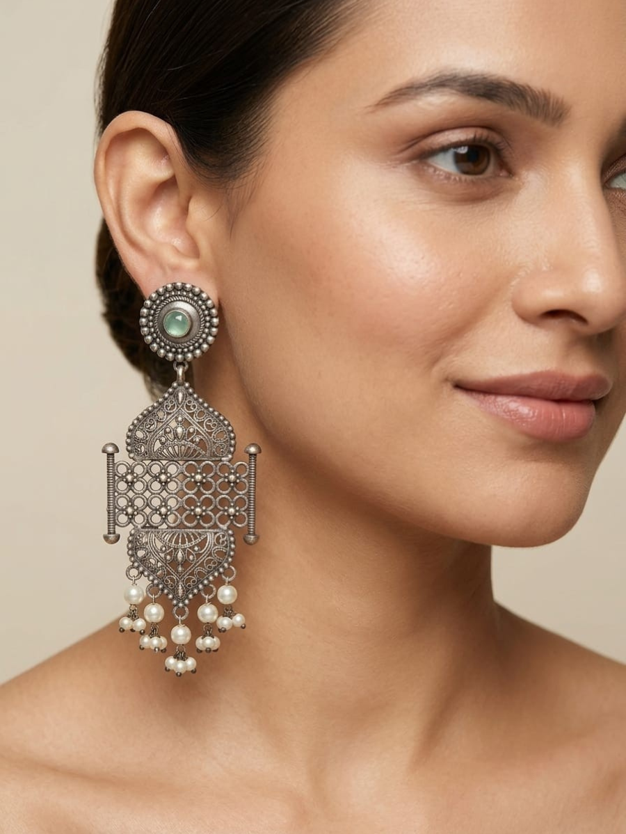 A model is wearing our Traditional Green Stone Oxidized Statement Earrings