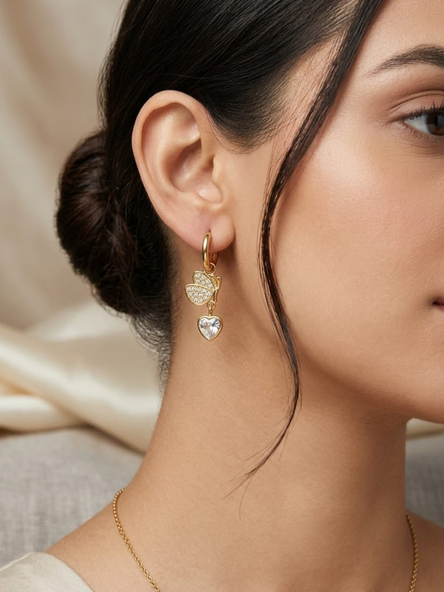 A model is wearing our Trendy Butterfly and Heart Drop Golden Huggie Hoop Earrings