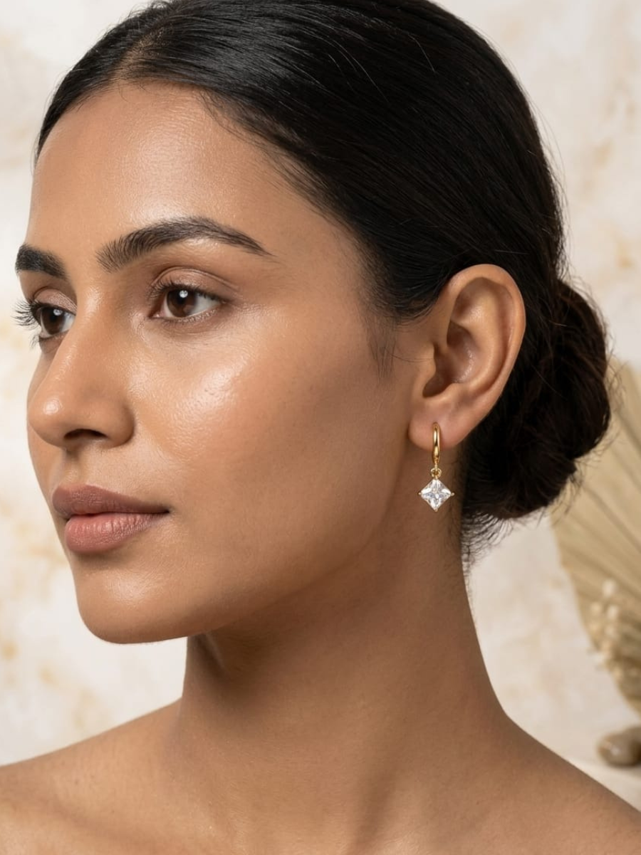 A model is wearing our Trendy Square White Stone Drop Golden Huggie Hoop Earrings