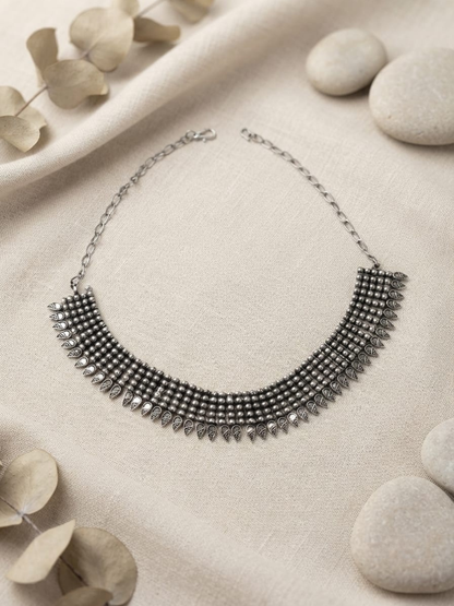 A silver-toned statement collar necklace with intricate beaded and filigree details