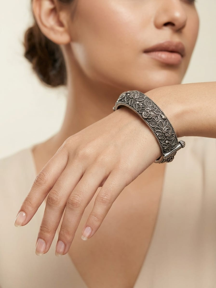 A model is wearing our Flower Style German Silver Oxidised Thin Kada Bangle
