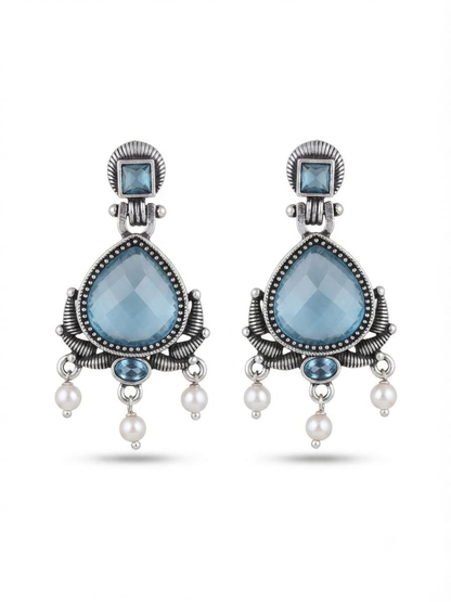 A pair of silver-toned statement dangle earrings featuring faceted light blue teardrop-shaped crystals, smaller blue stones, and dangling white pearl beads
