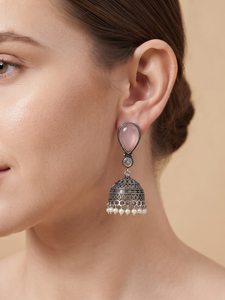 A woman showcasing traditional Indian oxidized jhumkas with pink stones and pearls