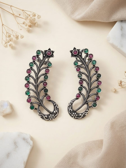A pair of earcuff silver-toned leaf-shaped earrings decorated with alternating green and pink gemstones