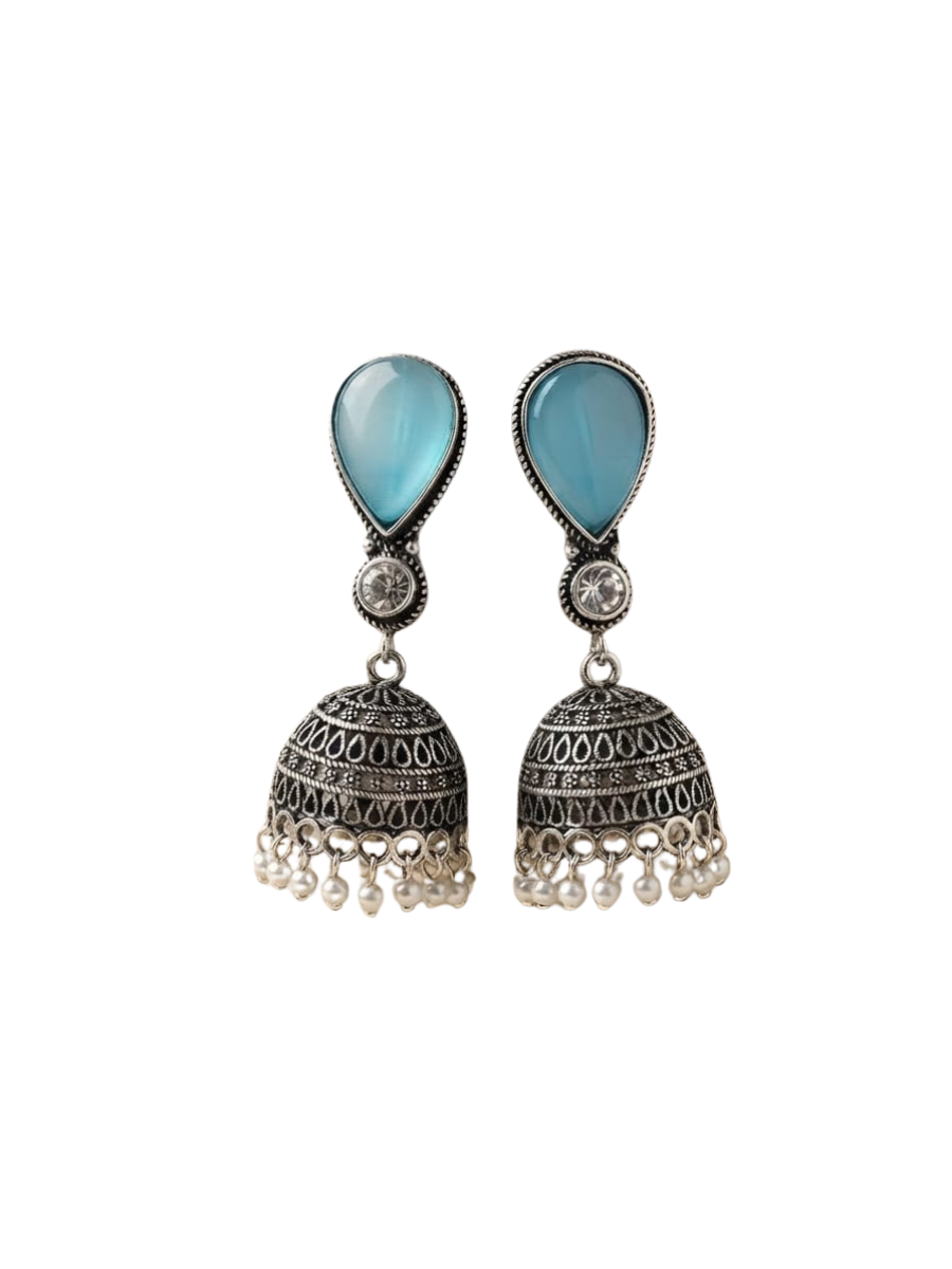 A pair of traditional Indian jhumka earrings featuring light blue teardrop-shaped stones at the top and ornate silver filigree bell-shaped drops with dangling pearls
