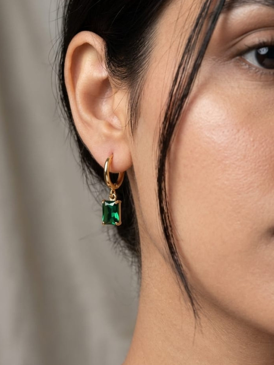 A model is wearing our Rectangular Green Stone Drop Golden Huggie Hoop Earrings