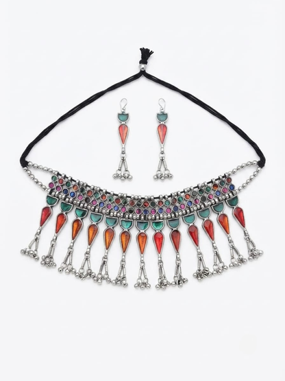 A bohemian-style silver necklace and matching drop earrings set. The necklace features a black cord, a silver-toned collar decorated with multicolored rhinestones, and dangling silver teardrop charms embellished with red, orange, and turquoise stones.