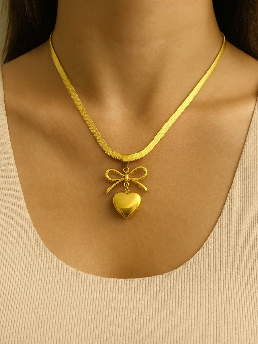 Gold necklace with a heart pendant and bow detail