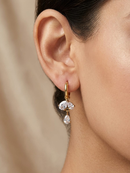 A model is wearing our Teardrop White Stones Golden Huggie Hoop Earrings