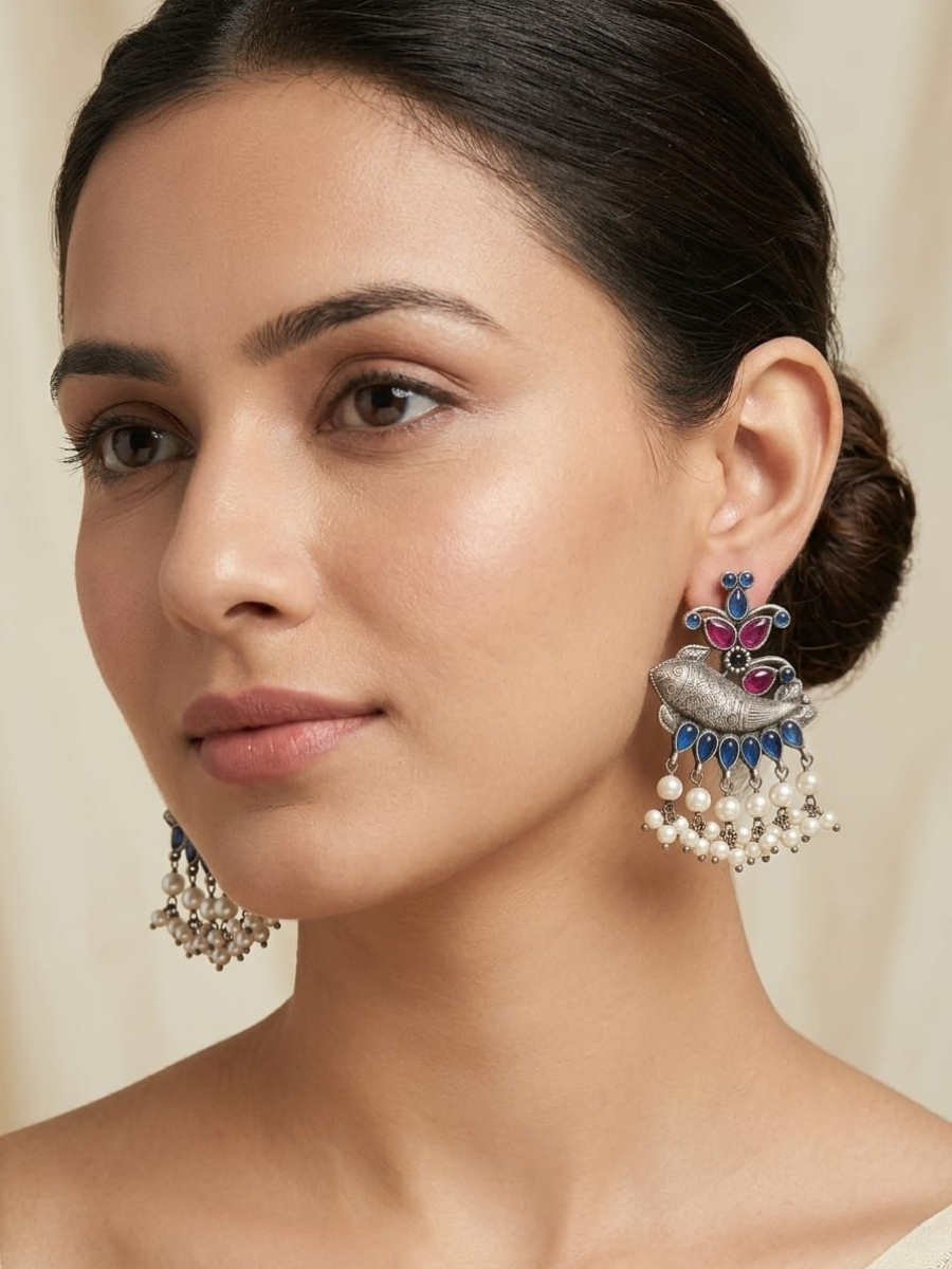 A model is wearing our Traditional Pink Blue Stones Oxidised Silver Fish Earrings