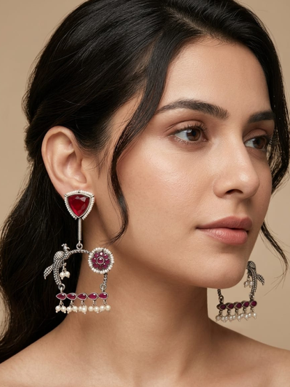 A model is wearing our Traditional Red Stones Peacock Motif Oxidised Earrings