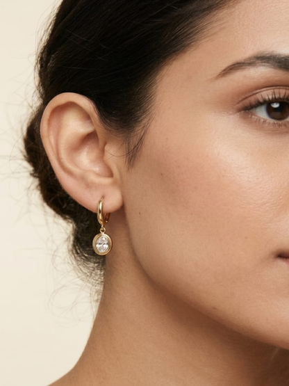 A model is wearing our Trendy White Stone Oval Drop Golden Huggie Hoop Earrings